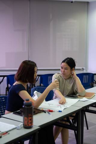 Two students discussing coursework across a table at Cambright