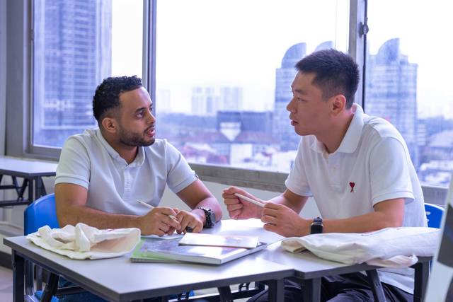 Two students discussing coursework across a table at Cambright